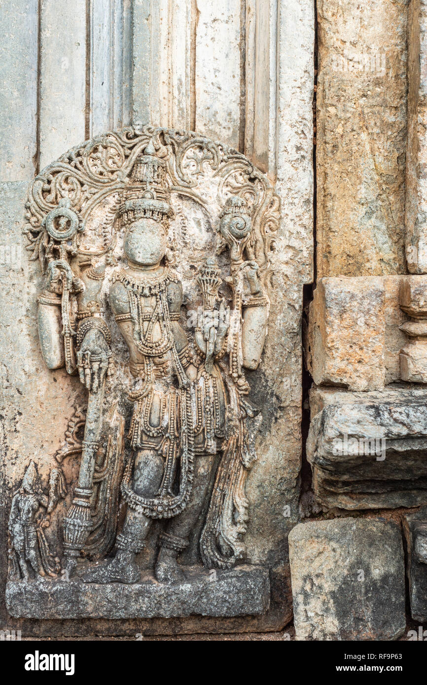 Belavadi, Karnataka, Indien - November 2, 2013: veera Narayana Tempel. Nahaufnahme von braunem Stein Skulptur von Lord Vishnu gegen die Wand außerhalb Eintrag h Stockfoto