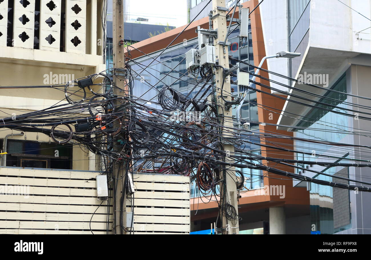 Nahaufnahme der unordentlichen Strom- und Kommunikationsleitungen auf elektrischen Polen Stockfoto