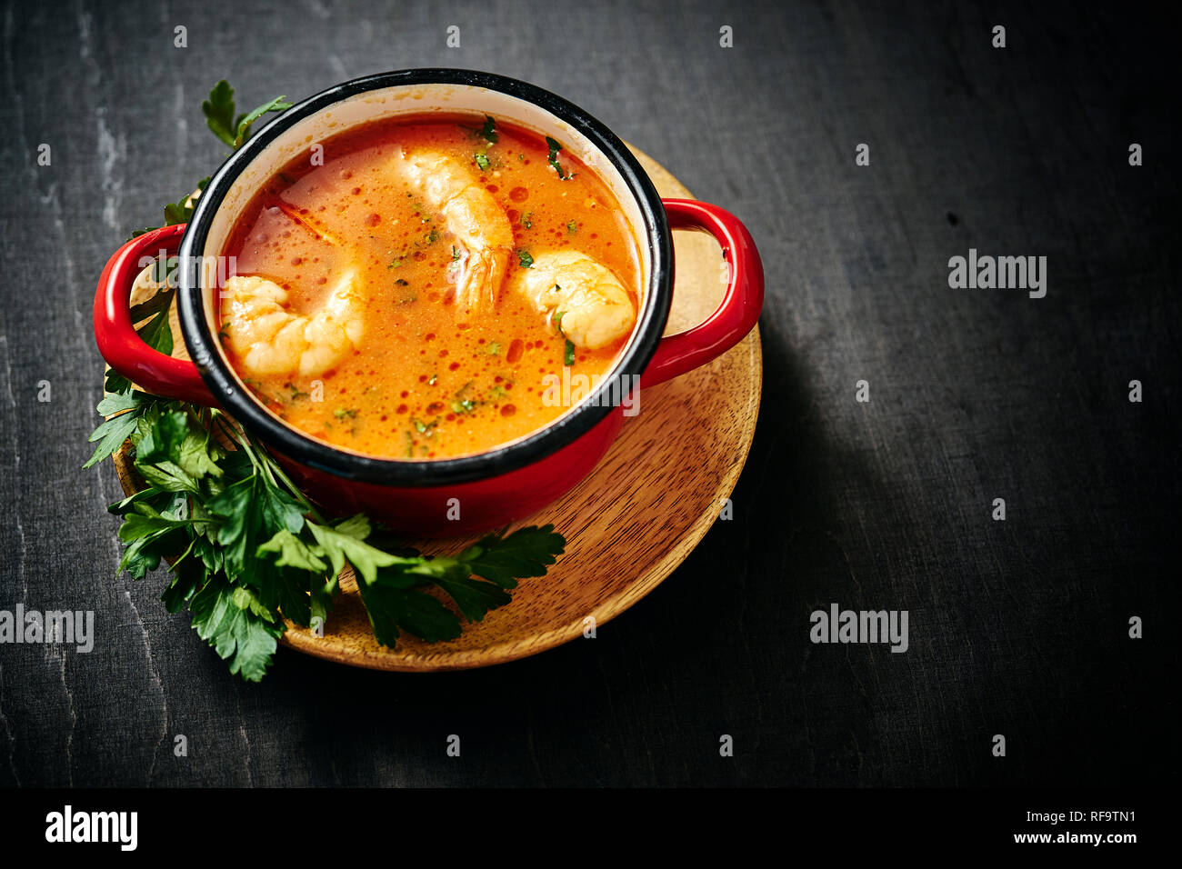 Traditionelle thailändische Suppe mit Garnelen und Kokosmilch in einem roten Topf mit Petersilie Stockfoto