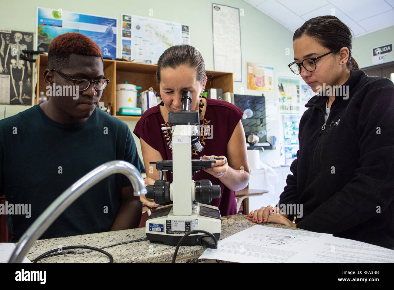Ein Foto von einem Lehrer und zwei internationale Studenten. Der Lehrer ist die Studenten mit einem Mikroskop. Stockfoto