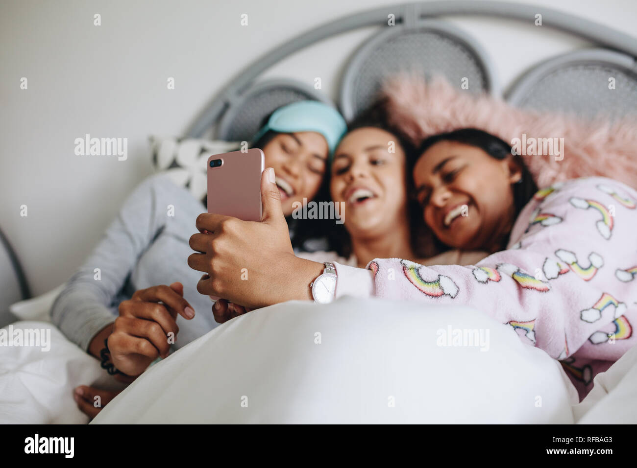 Mädchen liegen auf dem Bett Spaß ein selfie. Drei junge Mädchen genießen  Sie einen Film auf Handys bei sleepover Beim liegen auf dem Bett  Stockfotografie - Alamy