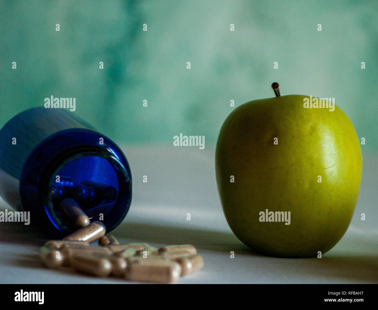 Einen Apfel und eine blaue Container mit pflanzenfasern Pillen auf einem Tisch Stockfoto