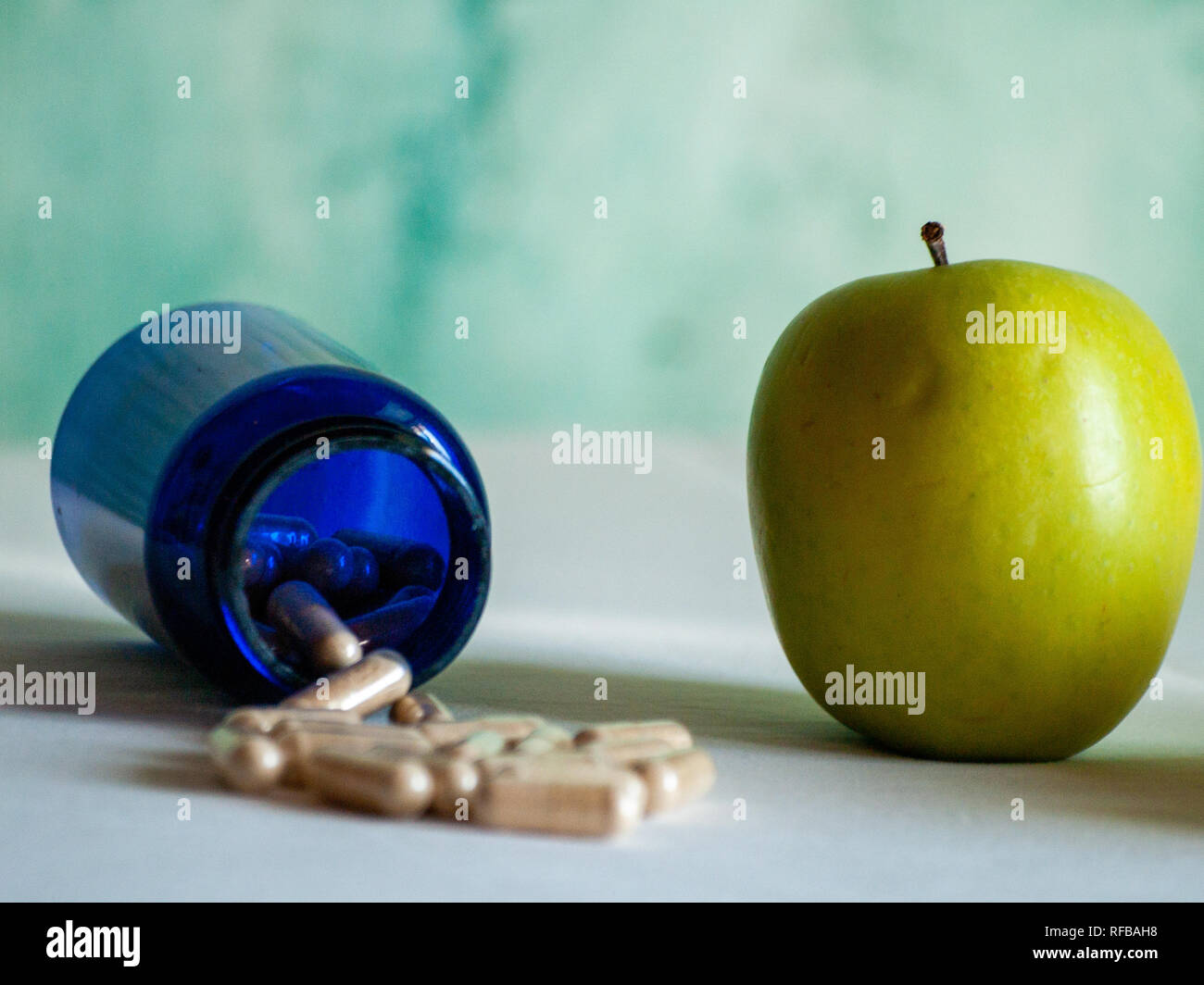 Einen Apfel und eine blaue Container mit pflanzenfasern Pillen auf einem Tisch Stockfoto