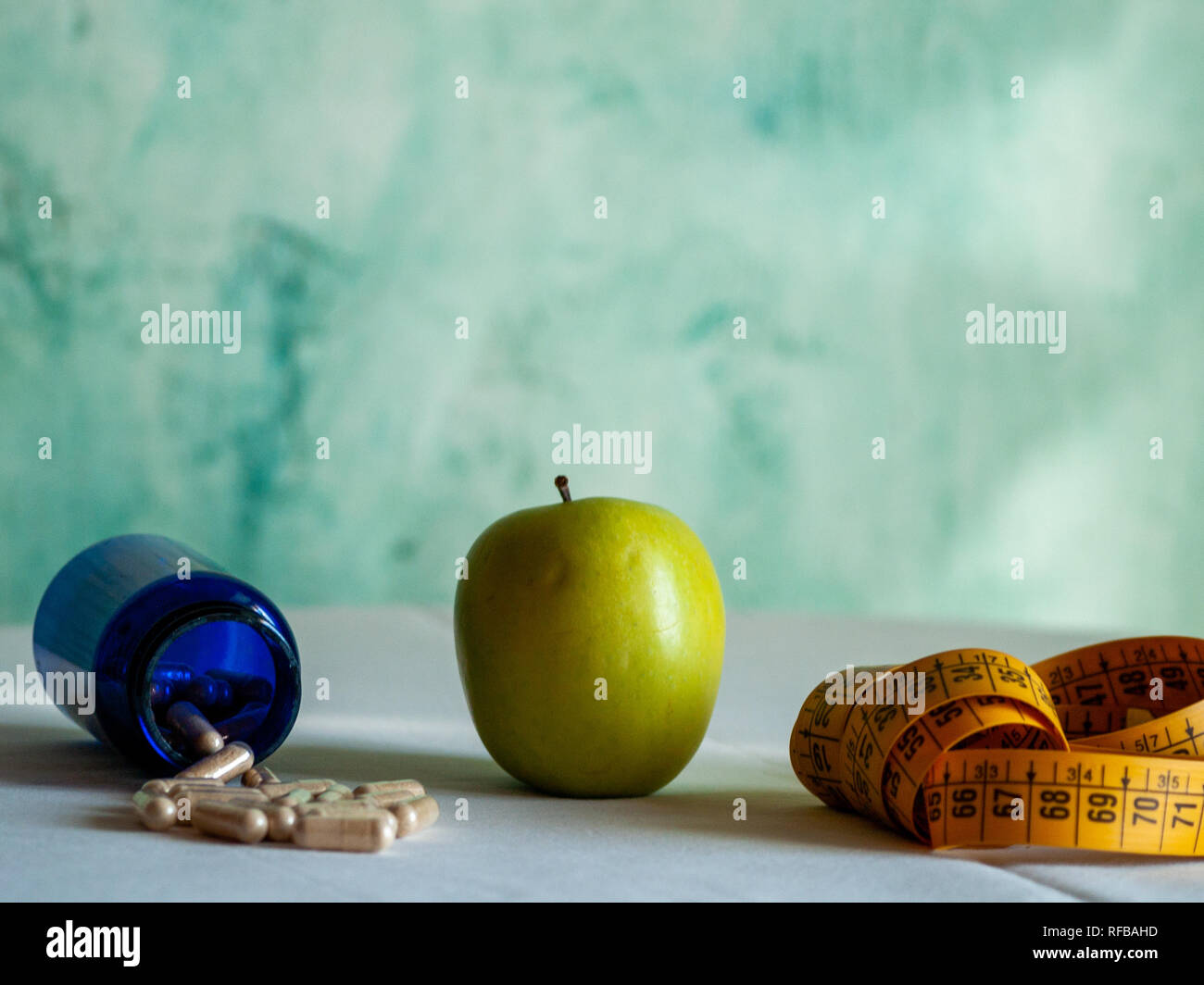 Ein Apfel, ein Maßband und einem blauen Container mit pflanzenfasern Pillen auf einem Tisch Stockfoto