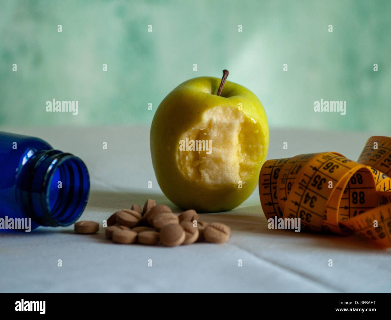 Eine gebissen Apple, ein Maßband und einem blauen Container mit pflanzenfasern Pillen auf einem Tisch Stockfoto