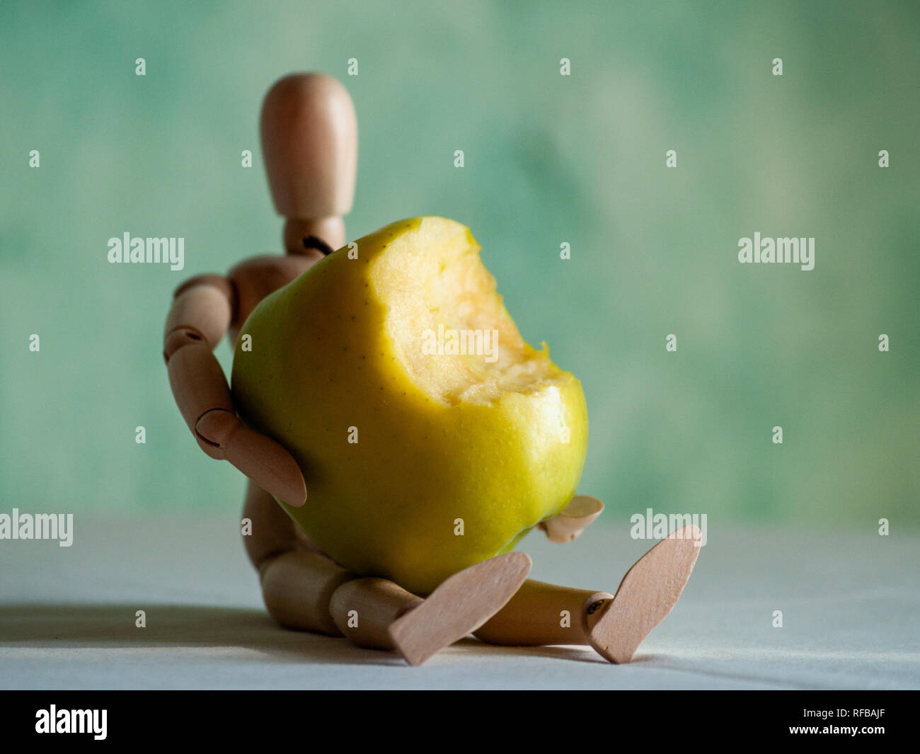 Eine hölzerne Figur mit einem gebissen Green Apple auf einem Tisch Stockfoto