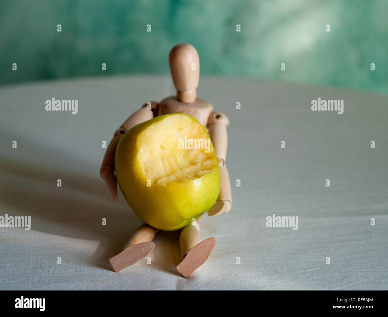 Eine hölzerne Figur mit einem gebissen Green Apple auf einem Tisch Stockfoto
