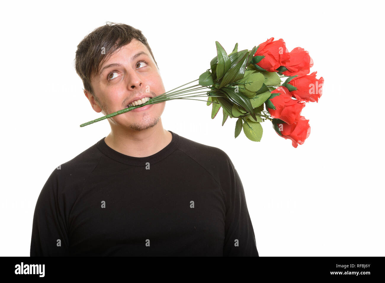 Studio shot verrückter Kaukasischen Menschen beißen rote Rosen und Denken Stockfoto