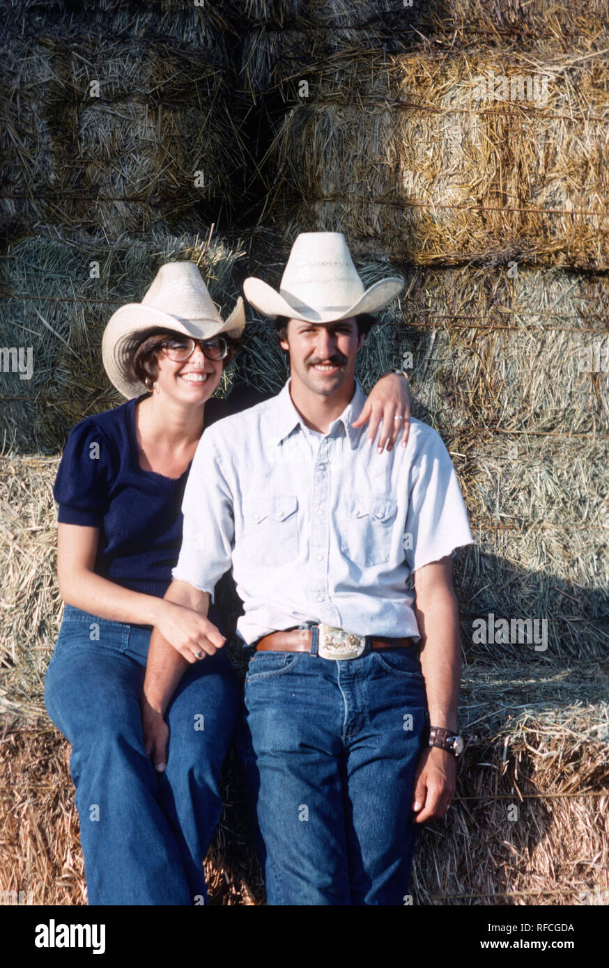 Junges Paar Posieren vor der Heuballen auf ihren jRanch, 1976., MT, USA Stockfoto