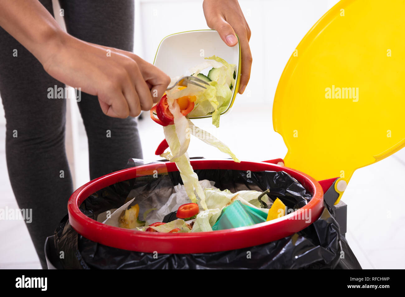 Nahaufnahme von einer Frau Hand werfen Salat in der offenen Papierkorb Stockfoto
