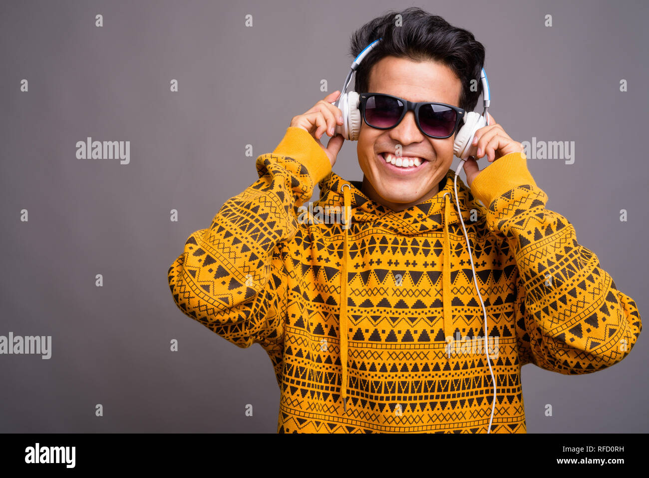 Jungen asiatischen Menschen hören die Musik gegen grauer Hintergrund Stockfoto