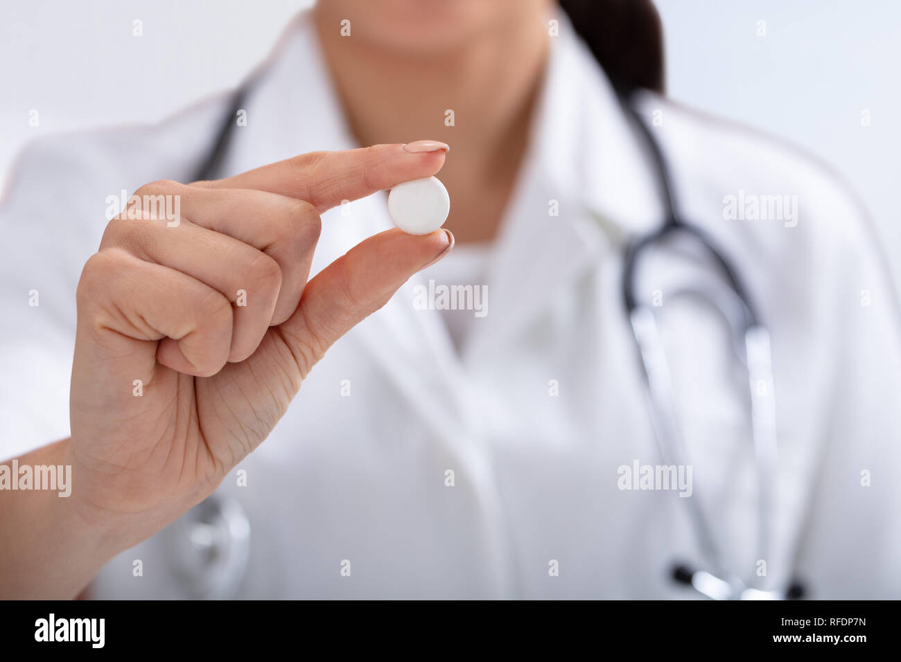 In der Nähe der weiblichen Doktor mit Stethoskop um den Hals halten weiße Tablette in der Hand Stockfoto