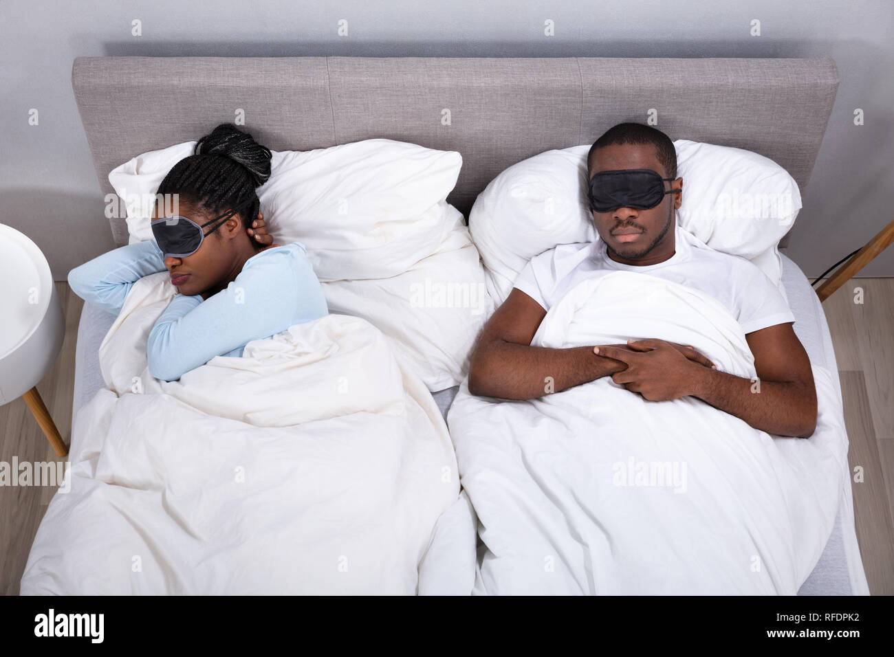 Junge afrikanische Paar schlafend auf dem Bett mit Augenmaske im Schlafzimmer Stockfoto