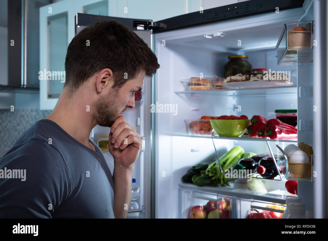 Schöner Mann auf der Suche nach Essen im Kühlschrank Stockfotografie - Alamy
