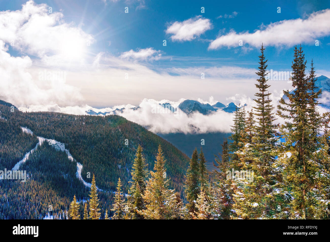 Morgensonne späht durch niedrige Wolken über die verschneite Berglandschaft von Lake Louise in den Kanadischen Rocky Mountains in der Nähe von Banff National Park, Kanada. Stockfoto