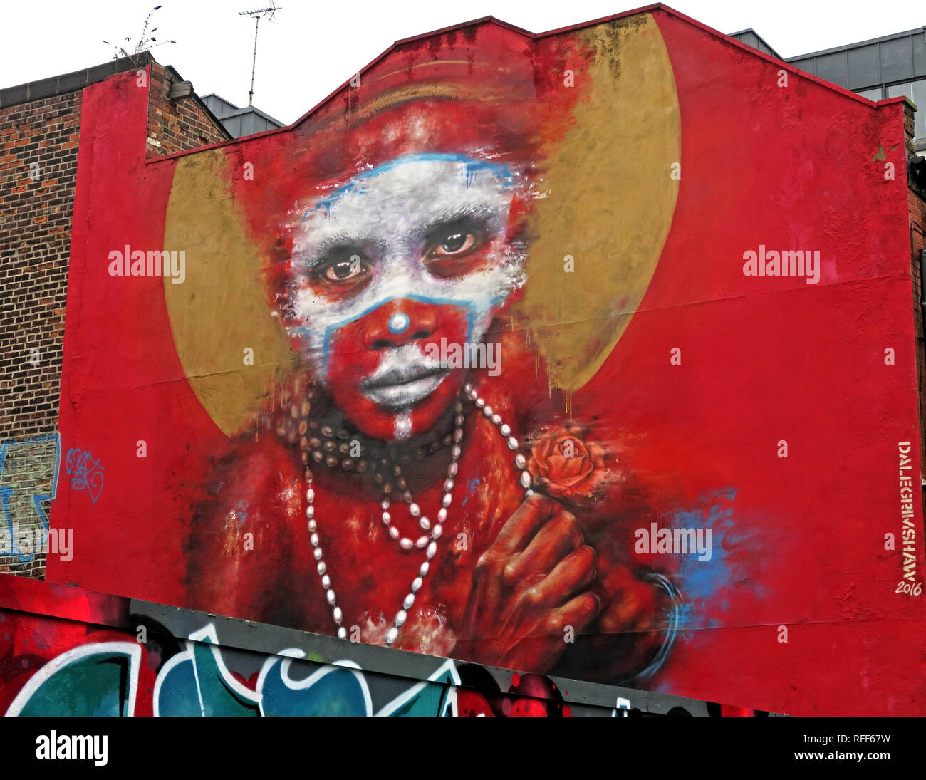 Aboriginal face auf rotem Hintergrund von Graffiti, Speer St, Northern Quarter, Manchester, England, Großbritannien Stockfoto