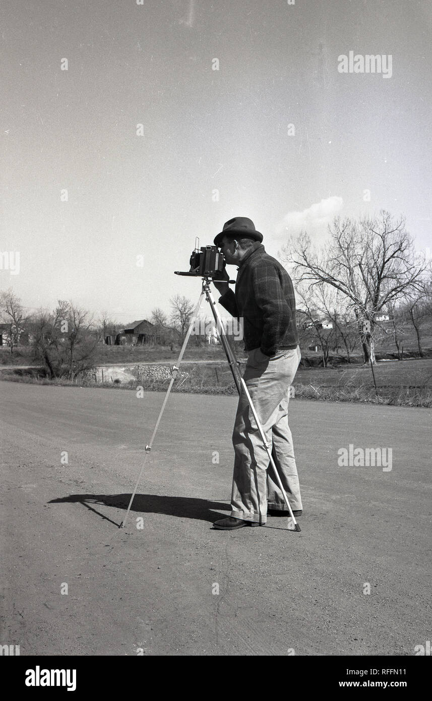1950, historische, erwachsenen männlichen Fotografen mit einem großformatigen fotografischen Film Kamera auf einem Stativ außerhalb, USA. Stockfoto