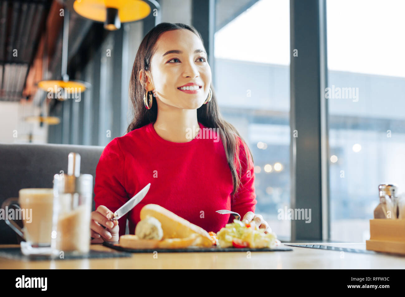 In der Nähe der strahlenden ansprechende Frau essen Frühstück im Cafe Stockfoto