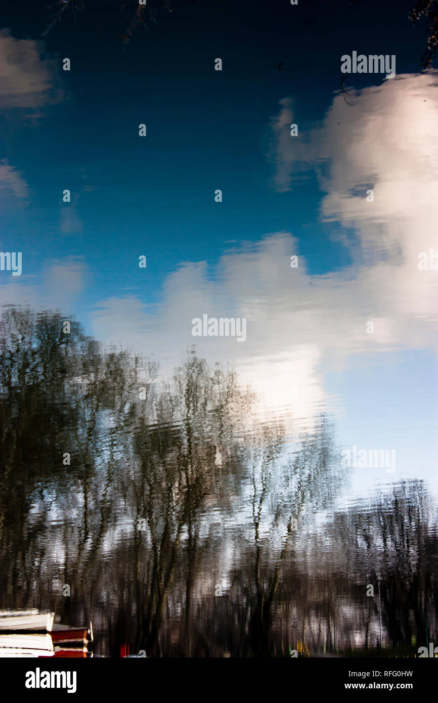 Blurry Natur, Reflexion von verankert kleine Boote, Wälder, blauer Himmel und Wolken im Wasser des Flusses Stockfoto