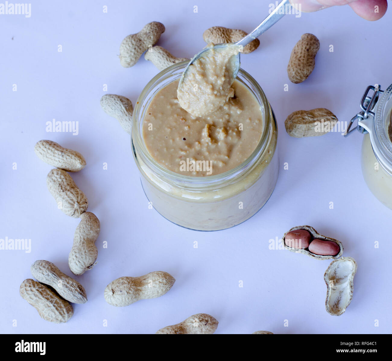 Selbstgemachte Erdnussbutter im Glas Glas mit Erdnüssen auf dem Tisch ausgebreitet Stockfoto