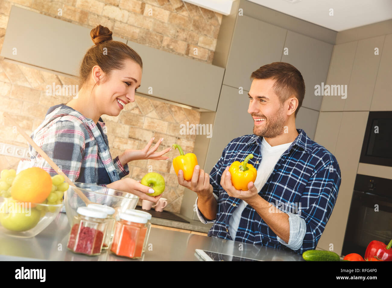 Junges Paar zu Hause in der Küche spielen zusammen mit Gemüse heiter Stockfoto