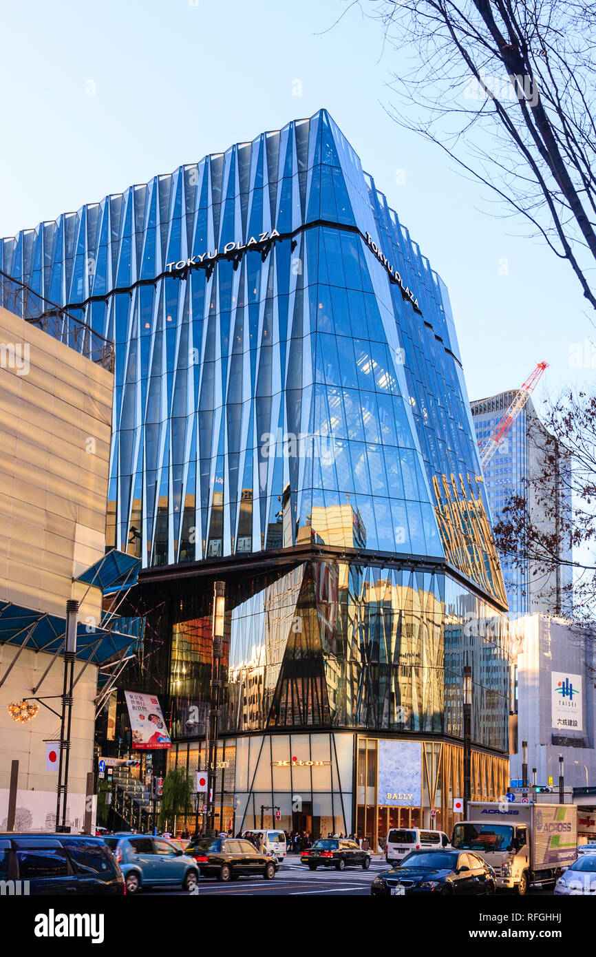 Die Tokyo Ginza. Verkehr fahren vorbei an der riesigen Tokyu Plaza Gebäude mit Bally store Eingang an der Ecke. Japanische Flaggen hängen von Straßenlaternen Stockfoto