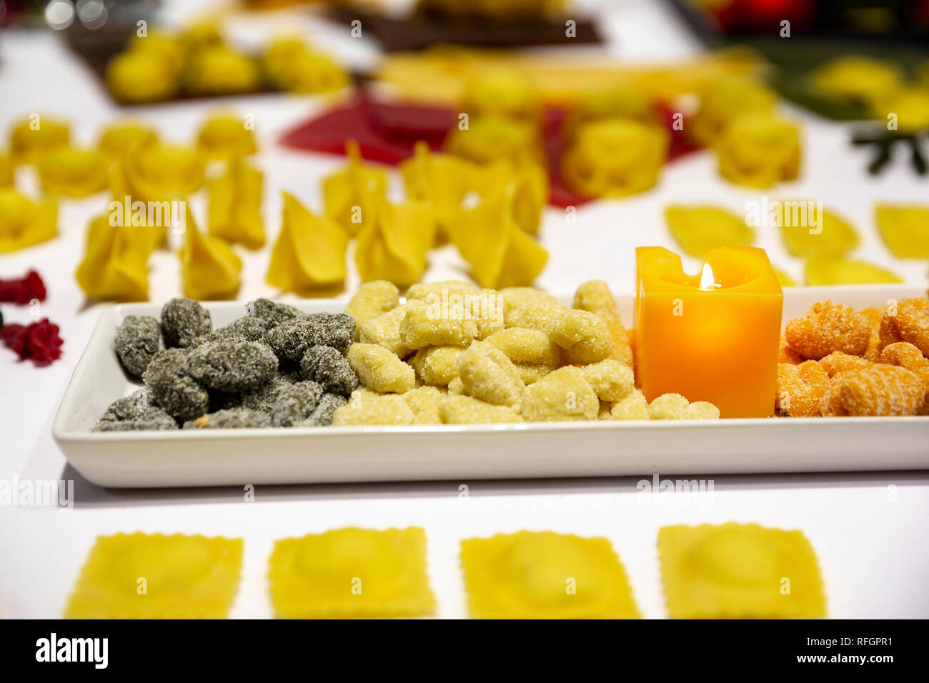 Verschiedene Arten von italienischer Pasta. Verschiedene Farben von Nudeln in Platten mit Kerzen gesehen von oben. Stockfoto