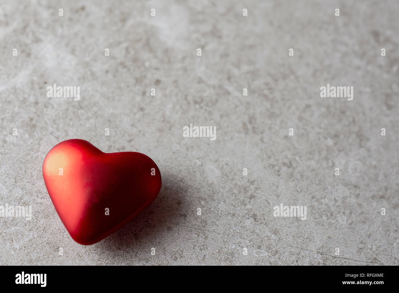 Nahaufnahme von einem einzigen Satin rot Herz mit Schatten auf einem braunen Hintergrund. Viel Platz kopieren. Hintergrund verschwommen. Stockfoto