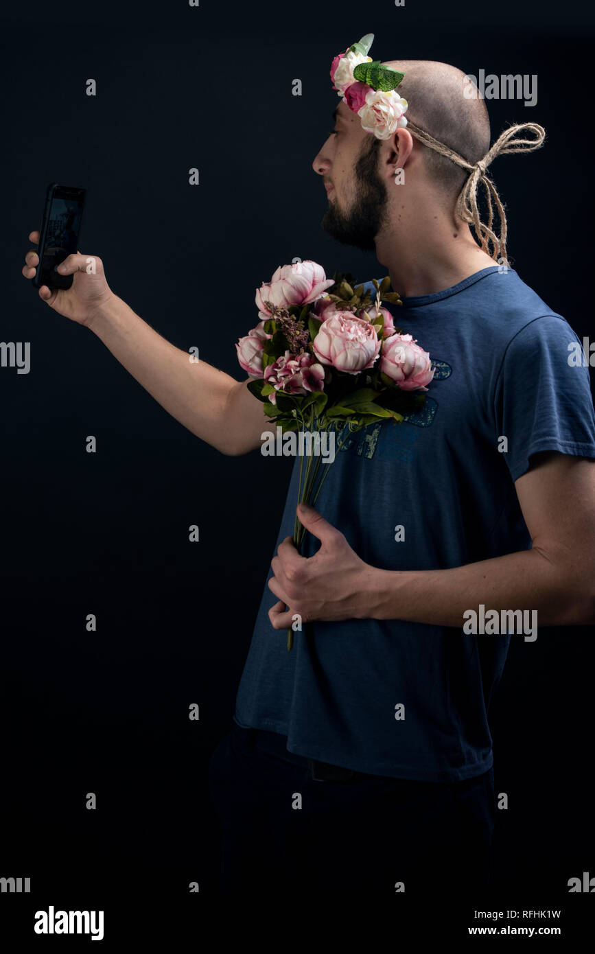 Männliche Blüten tragen, Haarband und halten einen Blumenstrauß ist selbst ein selfie. Romanische Geschenk für den Valentinstag Stockfoto