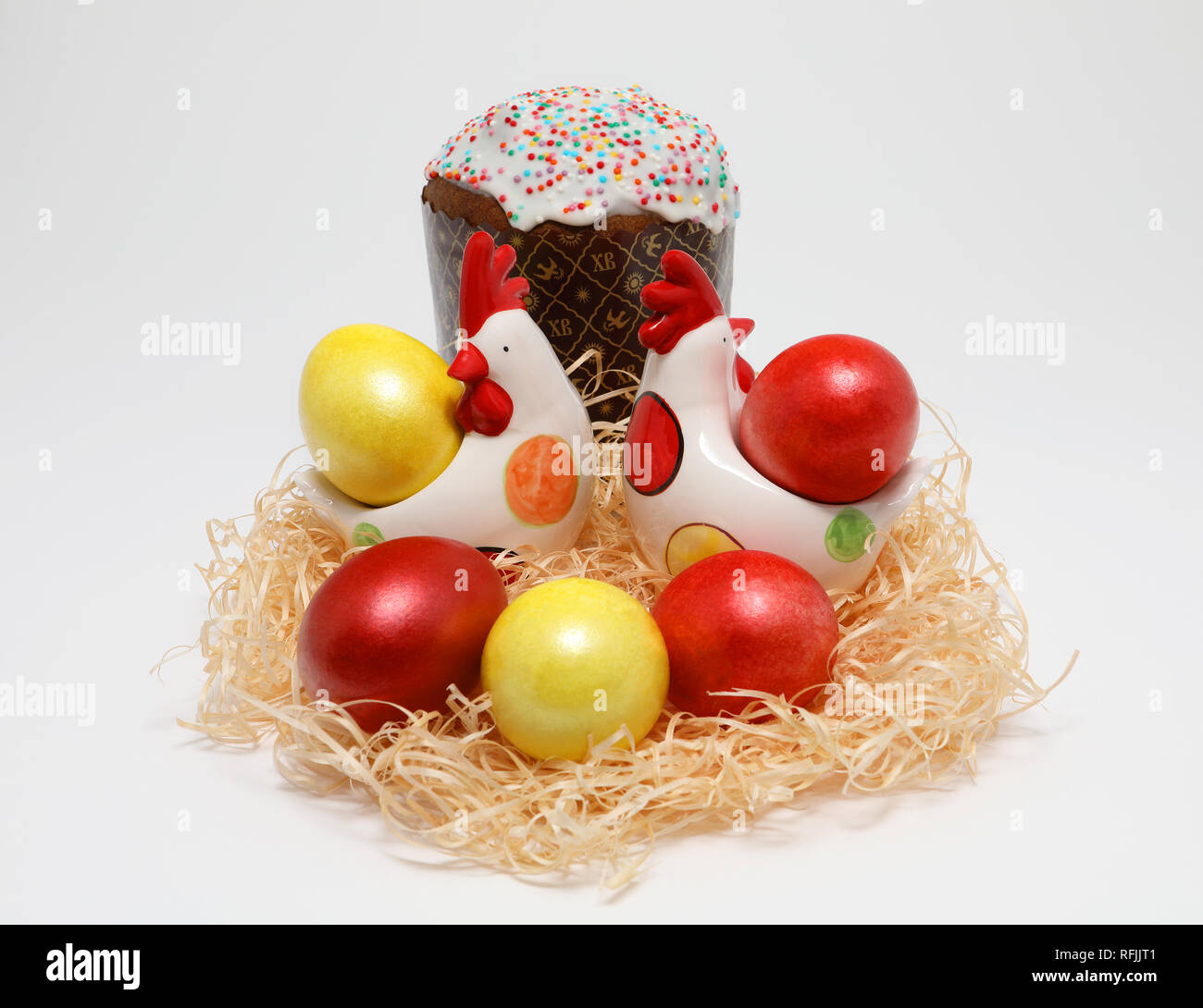 Fünf bunte Ostereier Farben rot und gold in zwei toy Legehennen in einem Nest und Ostern Kuchen auf weißem Hintergrund, Feder Bild. Ostern Konzept. Stockfoto