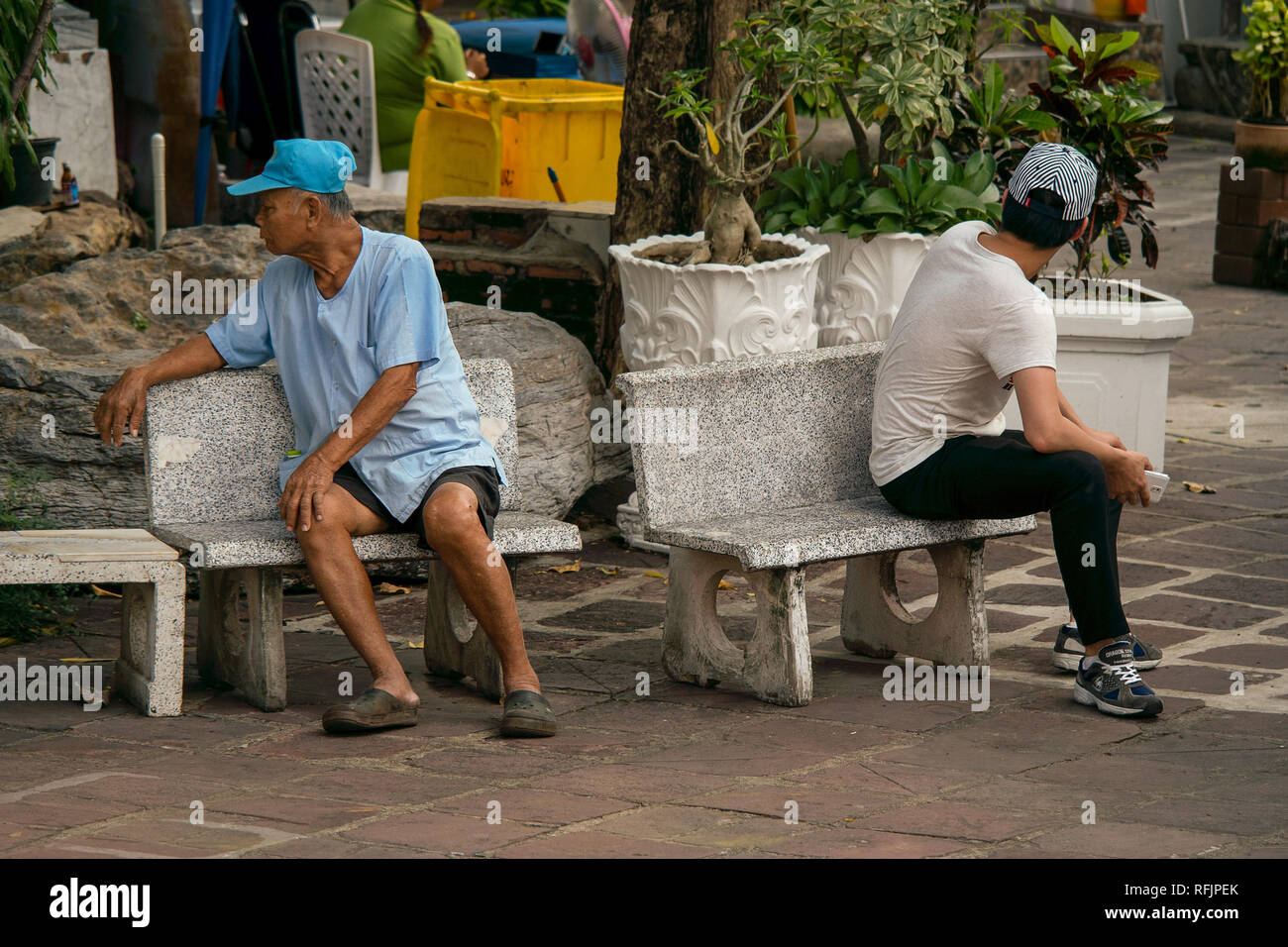 Ein älterer Mann und der junge Mann setzte sich wieder komisch, wieder auf der Suche nach einander in die falsche Richtung. Stockfoto