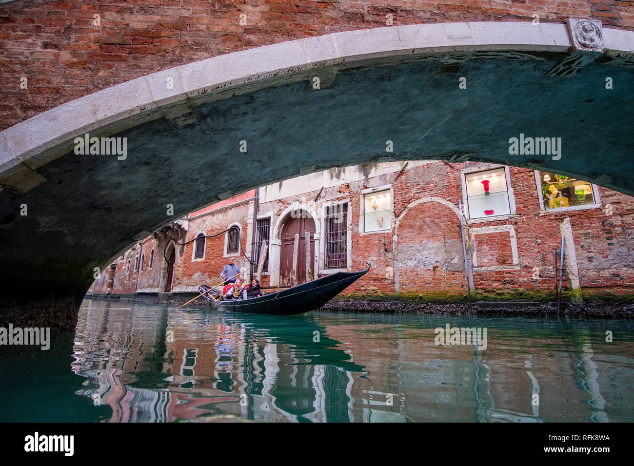 Eine Gondel, die traditionellen venezianischen Ruderboot, Kreuzfahrt auf einem kleinen Kanal zwischen dem maroden gemauerte Häuser der Stadt, vorbei an einem Stein ar Stockfoto