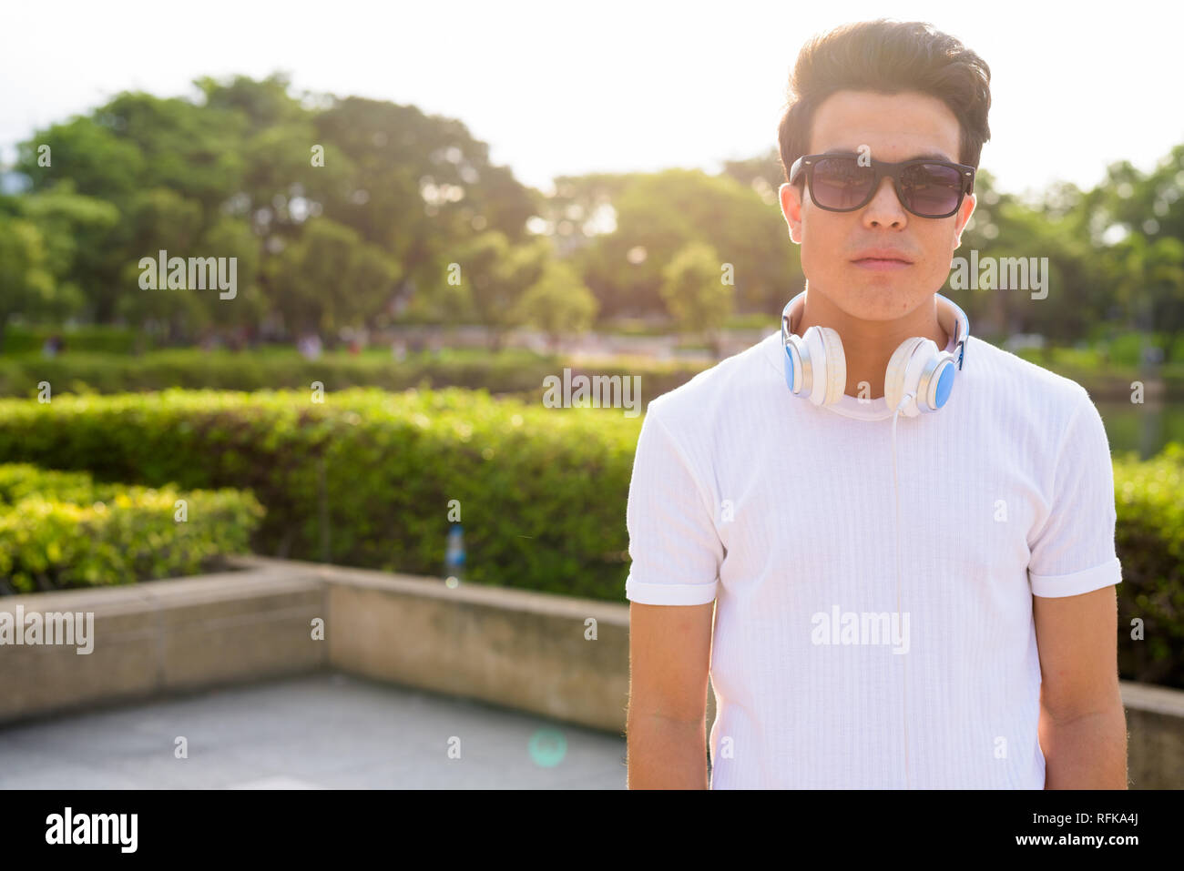 Junge asiatischer Mann Kopfhörer tragen, während sie sich im Park Stockfoto
