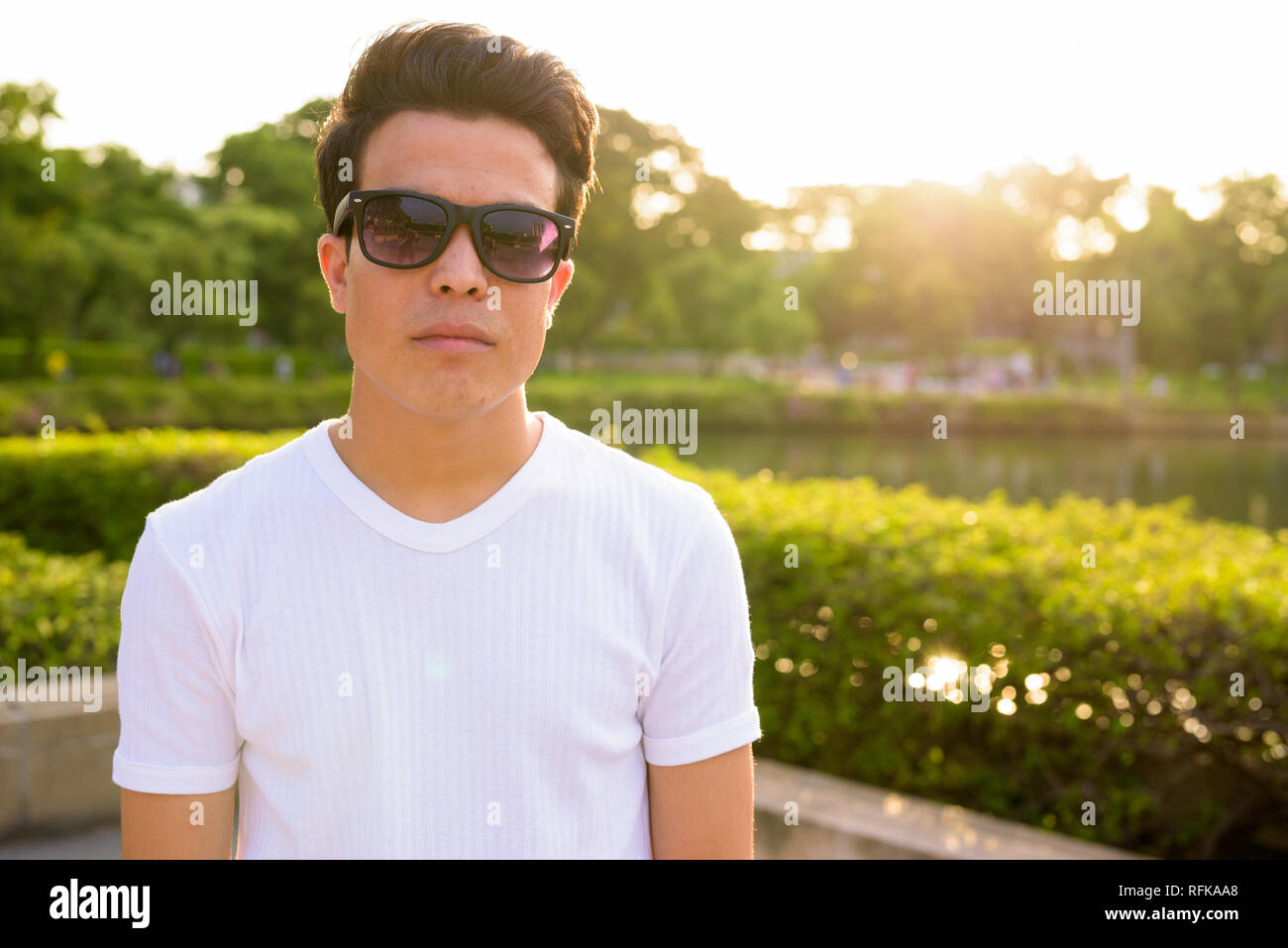 Junge asiatischer Mann Sonnenbrille tragen, während sie sich im Park Stockfoto