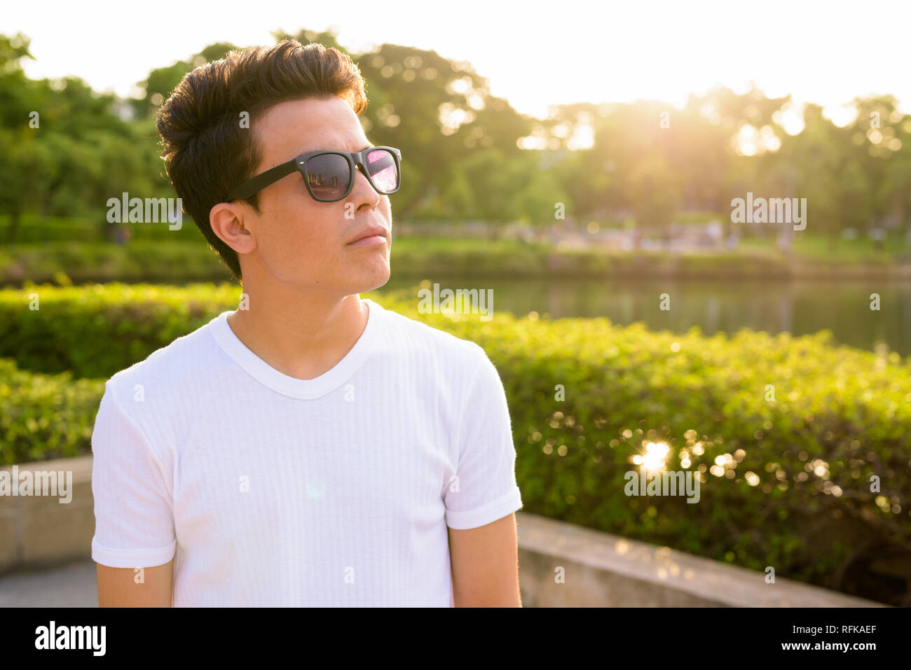 Junge asiatischer Mann Sonnenbrille tragen, während sie sich im Park Stockfoto