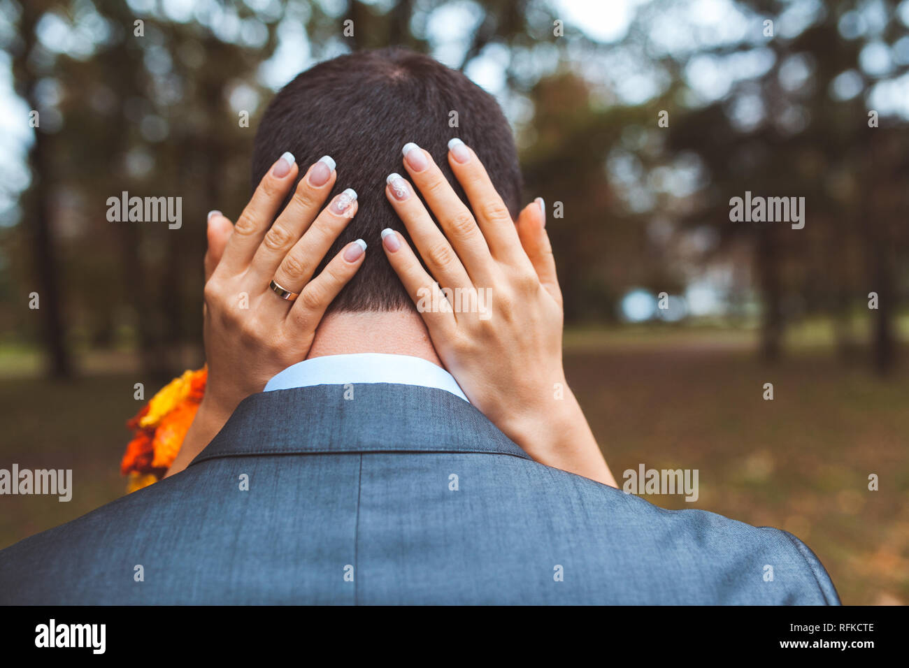 Frauen Arme um ein Männerkopf im Park an einem Tag Stockfoto