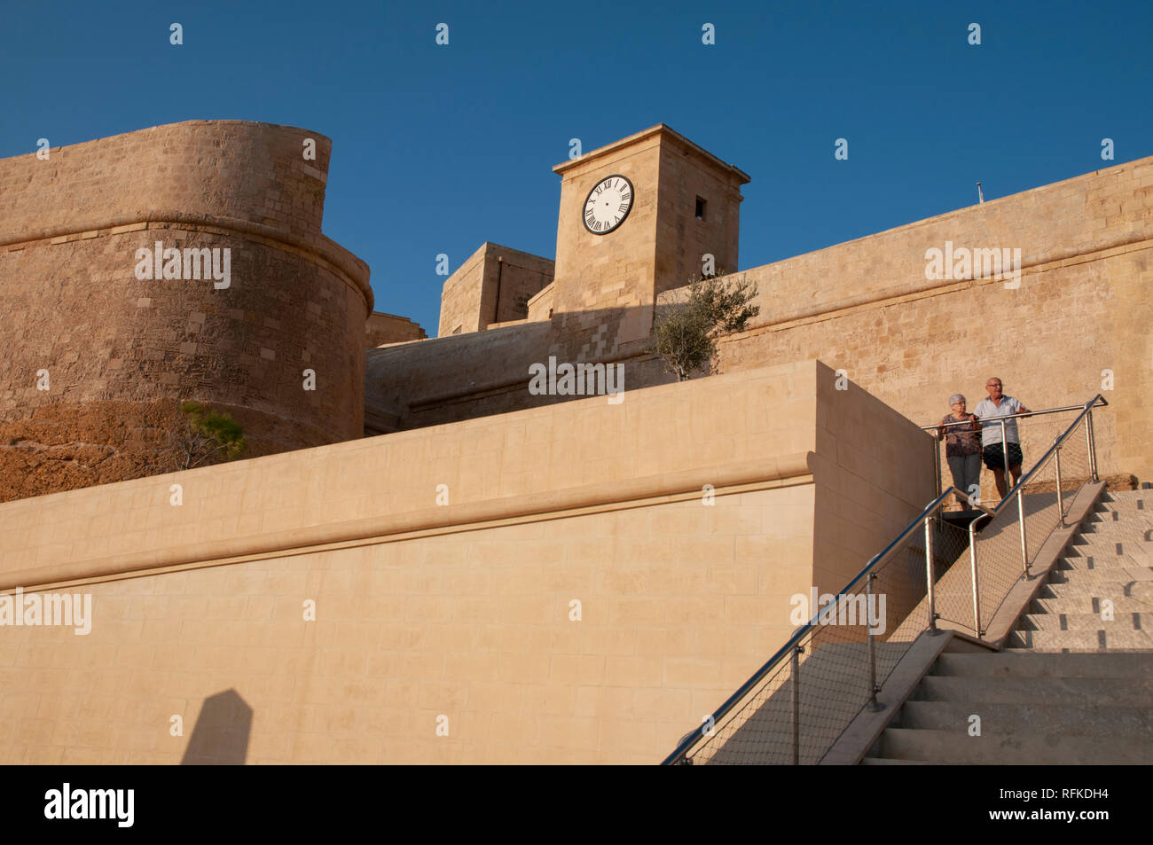 Ein älteres Ehepaar Stand im Bereich um den Haupteingang der Zitadelle Fort in Victoria, Gozo, Malta. Links ist der Hl. Martin Demi-Bastion. Stockfoto