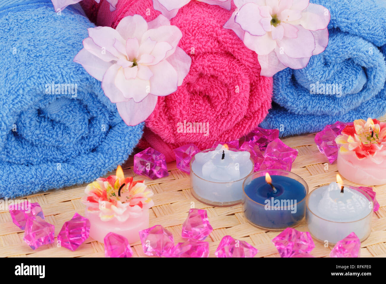 Bad mit Handtüchern, Kerzen und Blumen auf Bambus Hintergrund gesetzt. Stockfoto