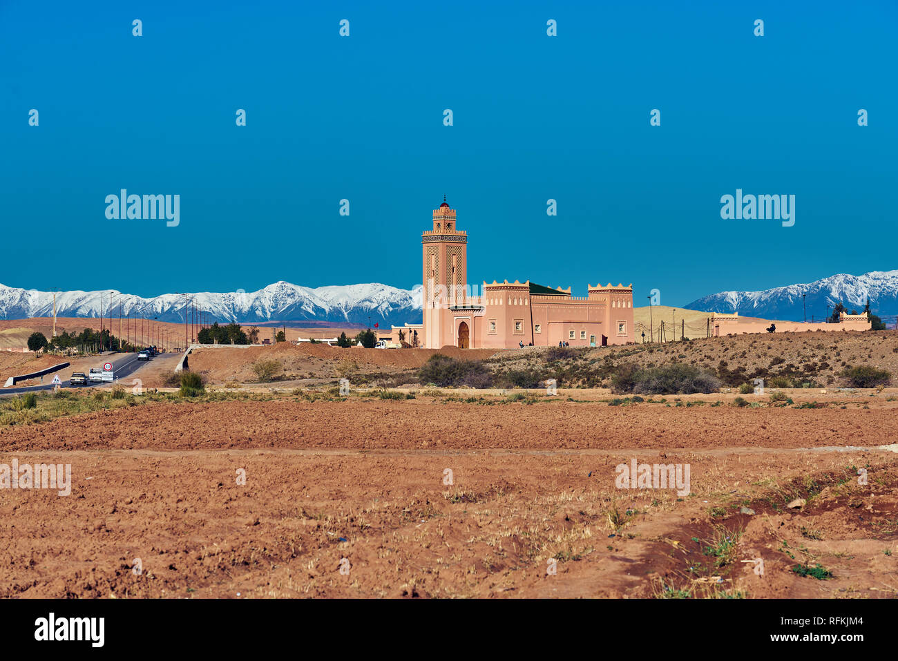 Landschaft einer traditionellen marokkanischen Moschee auf der Autobahn und verschneite Atlas-Berge. In Timedline, Provinz Ouarzazate, Marokko eingenommen Stockfoto