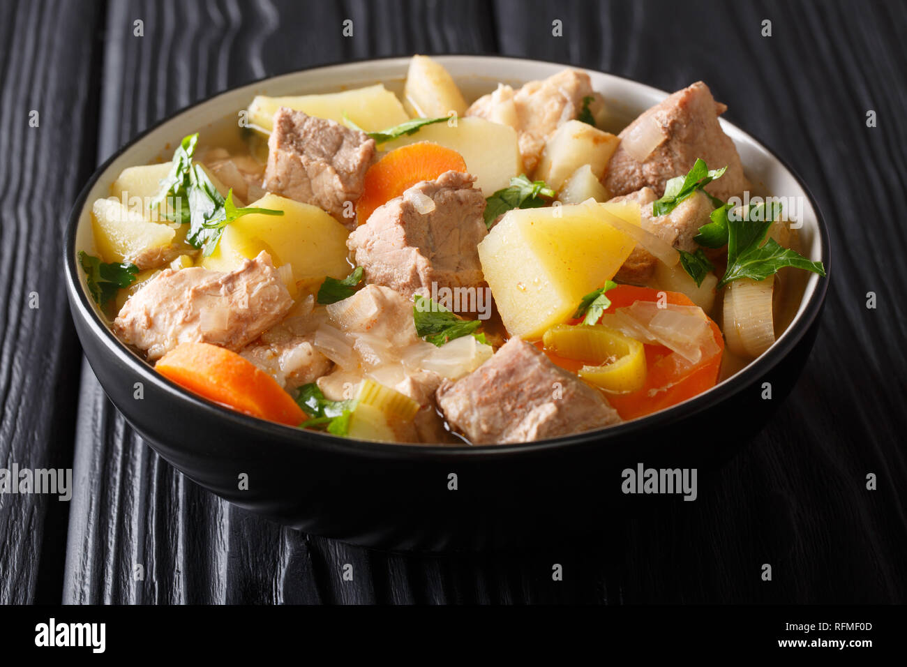 Deutsche Küche langsam gekocht Pichelsteiner mit Gemüse und Fleisch close-up in einer Schüssel auf einem Holztisch. Horizontale Stockfoto