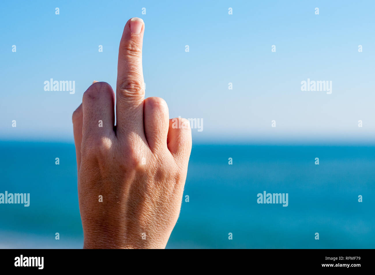 Handzeichen Mittelfinger zeigen nach oben, Gestik, Fuck off, Strand, Meer, Wasser Stockfoto