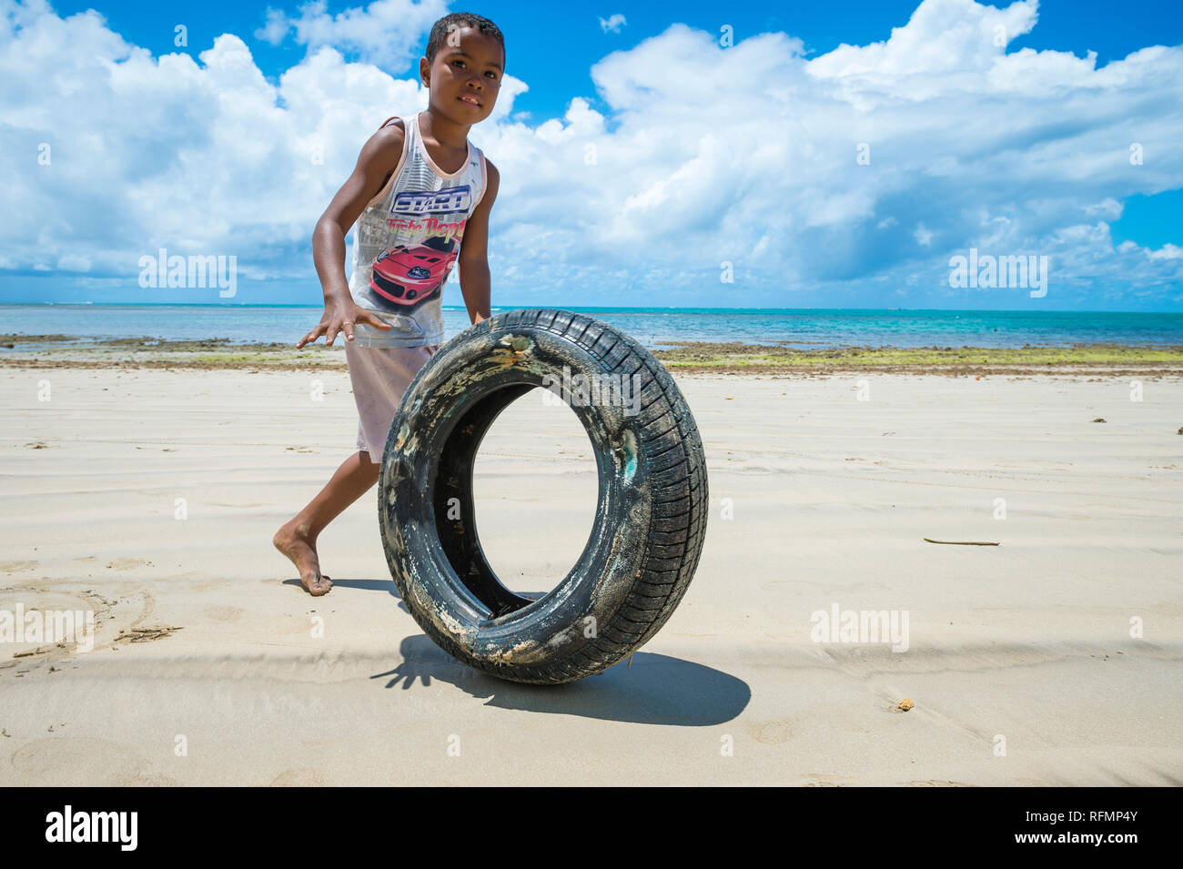 BAHIA, BRASILIEN - 15. FEBRUAR 2017: Eine junge Brasilianische rollt ein Reifen als Spiel auf einer leeren Strand auf einer einsamen Insel in ländlichen Nordeste. Stockfoto