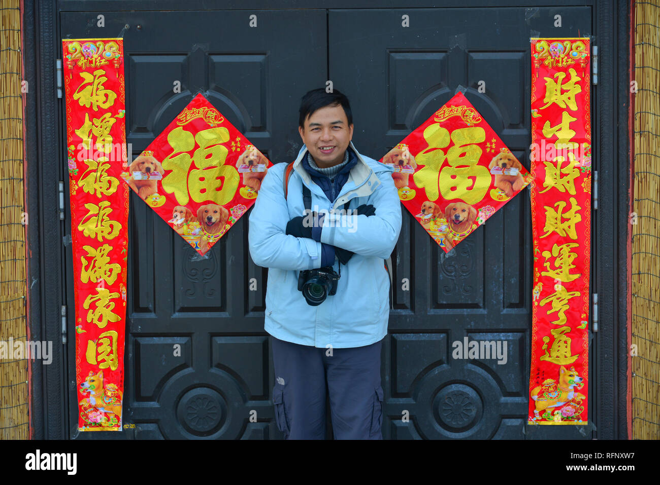 Harbin, China - Feb 23, 2018. Ein junger Mann stand vor der ländlichen Haus mit Dekorationen für Neujahr. Stockfoto