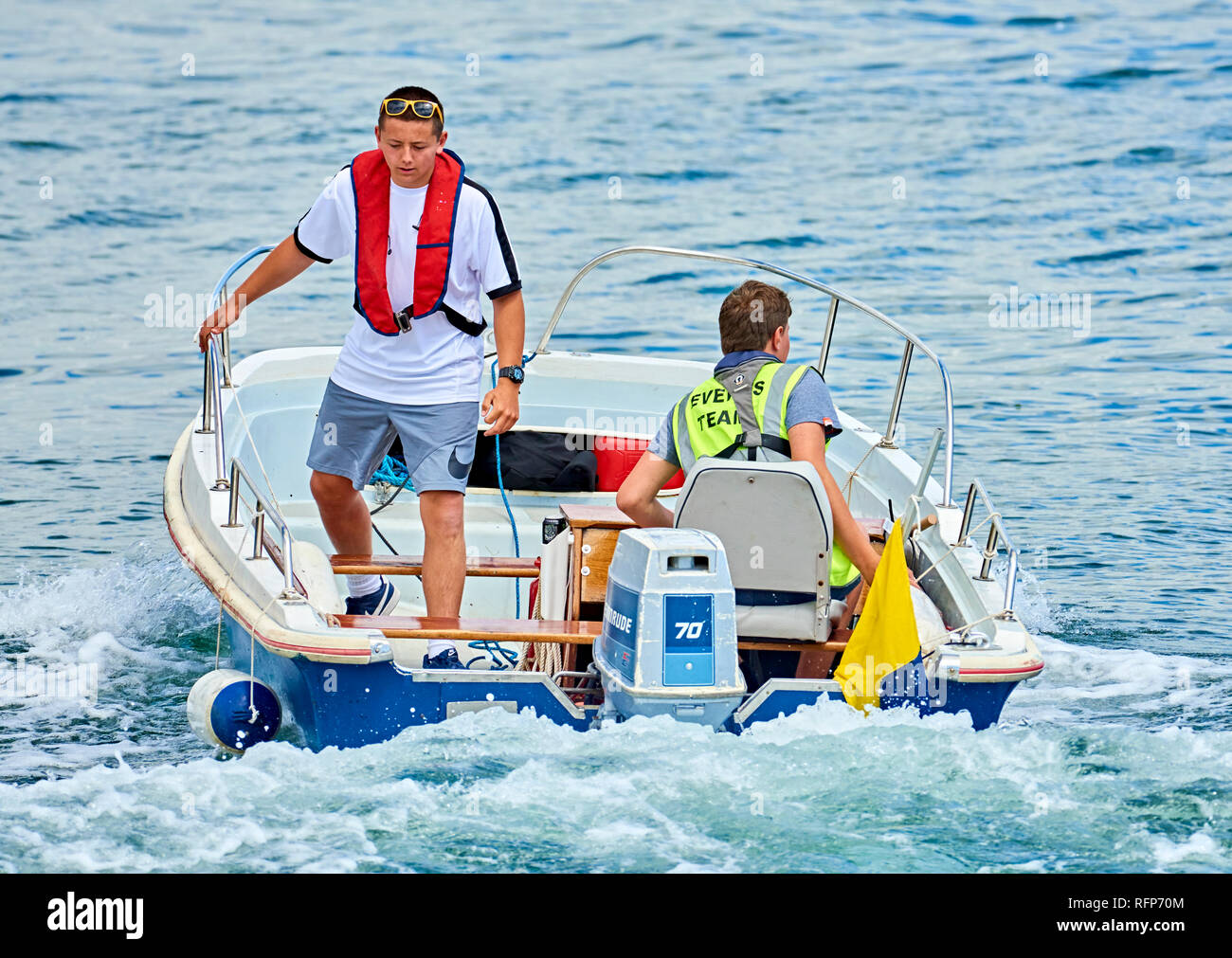 Zwei junge Männer betreiben eine kleine Sicherheit Boot an einer wässrigen Ereignis. Stockfoto