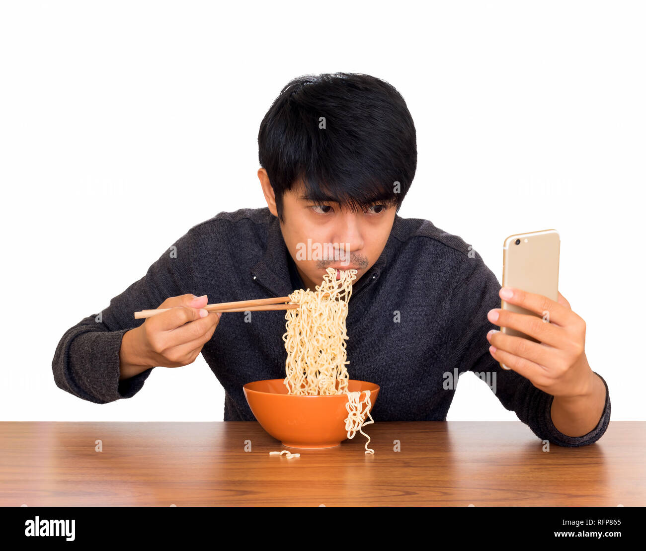 Mann essen chinesische Nudelsuppe monströs während der Suche und Verwendung von Smartphone isolieren auf weißem Hintergrund mit Freistellungspfaden. Konzept der Smartphone addict Stockfoto