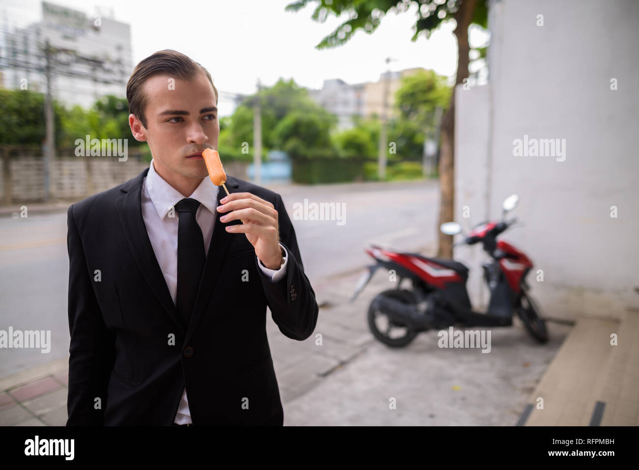 Junge Unternehmer essen Hot Dog Würstchen im Freien Stockfoto