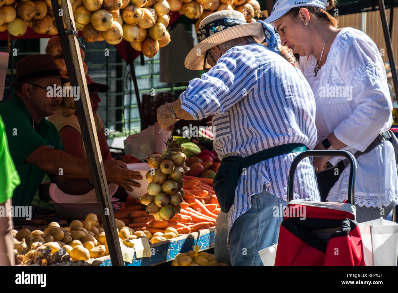 Ein Foto von einem Mann mit einem Sombrero kaufen ein Bündel von frischen Zwiebeln von einem lokalen Anbieter am Sonntag Bauernmarkt in Santa Ana Stockfoto