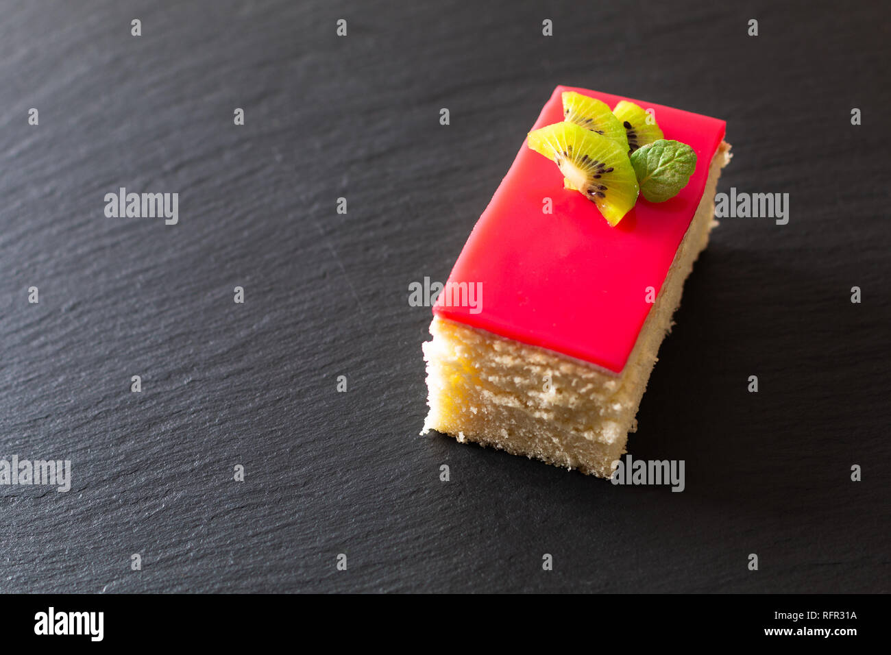Hausgemachte organische Stück vanille Biskuit rote Beere Soße auf schwarzem Schiefer Stein Platte mit Kopie Raum Stockfoto