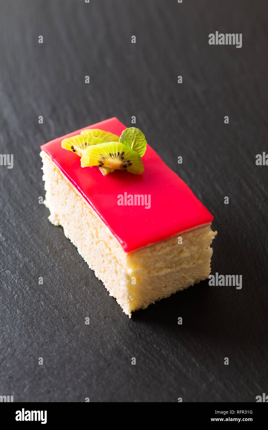 Hausgemachte organische Stück vanille Biskuit rote Beere Soße auf schwarzem Schiefer Stein Platte mit Kopie Raum Stockfoto