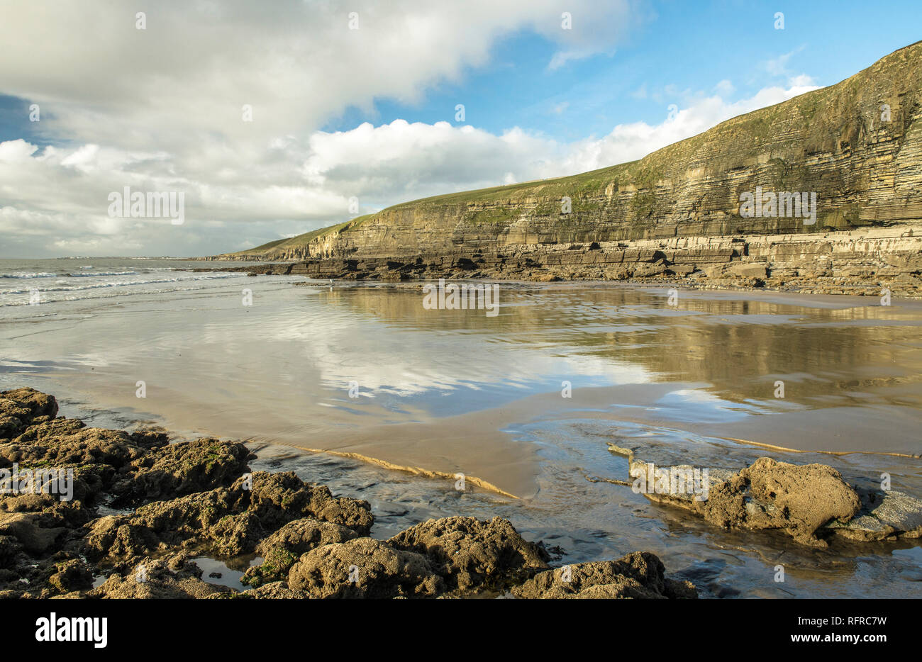 Dunraven Bay, Southerndown an der Glamorgan Heritage Coast. Der Winter Sonne verursacht cloud Reflexionen in den nassen Sand Stockfoto